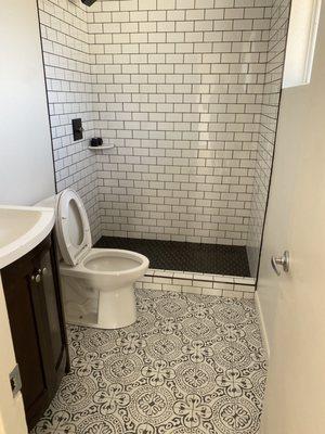 Subway Tile walk in shower with black grout and Moroccan black and white graphic floor tile