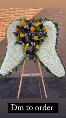 Funeral Wings, premium size. White wings with purple and yellow roses, some baby's breath and greenery.
Includes ribbon and stand.