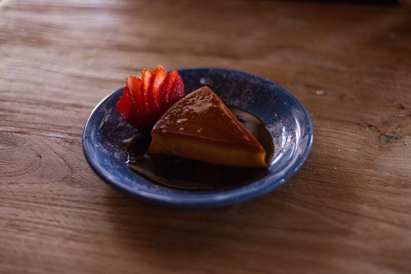 Flan with strawberries and chocolate sauce.