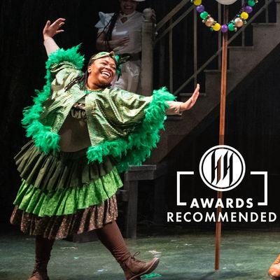 Performer in Green mardi Gras costume from Petite Rouge dances next to the Helen Hayes Award  logo