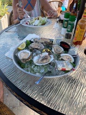 Oysters on the half shell and a wedge salad in the background.