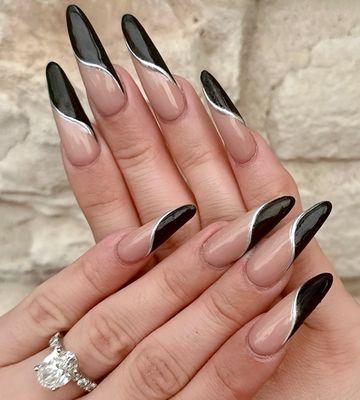 Stiletto nails with a nude base and bold black French tips for a dramatic look. #BlackFrenchTips #StilettoStyle