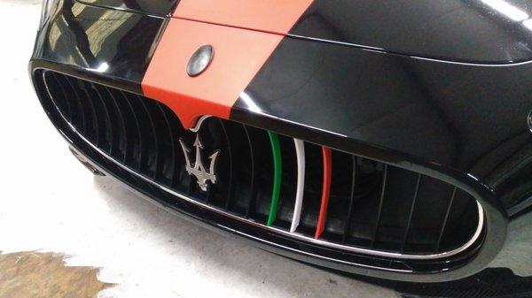 Maserati flat red stripe, flat black symbol, and Italian-flag colored accents on the grill fins.