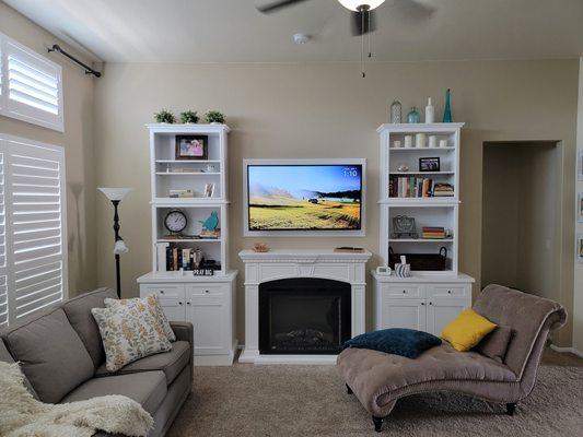 Electric fireplace mantle kit and semi-custom built ins, with a picture frame behind the TV.