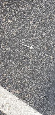 Needle in parking lot next to vehicles where kids play and ride their bikes