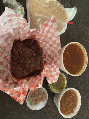 Pictured a pound of barbacoa, green salsa, pico de Gallo, menudo, complimentary beans and corn tortillas.