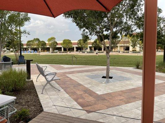 Wide green space with restaurants that have outdoor patios reaching the edges