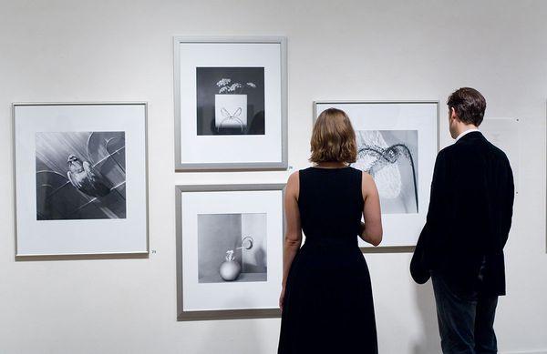 Two gallery patrons look at the gelatin silver prints of photographer, Frances Murray.