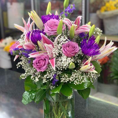 Vase arrangement with lily, roses, spider, baby's breath and greens.