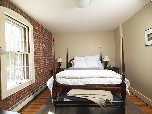 The Charlestown Room - An intimate room in soft gray and contrasted by an exposed brick wall.