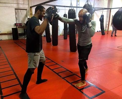 Trainer Devon Williams holding pads for client Justin Moore