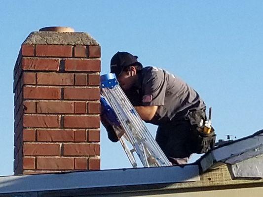 Diego fixing the fireplace brick/mortar on the roof.