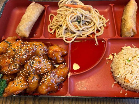 Lunch Bento withe Sesame Chicken,
 with eggroll, vegetable lomein, dish of the day, and fried rice.