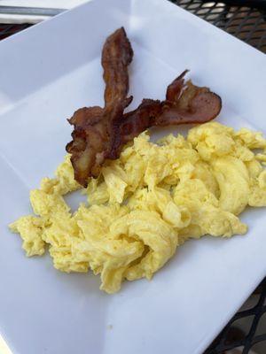 Scrambled eggs with two strips of bacon