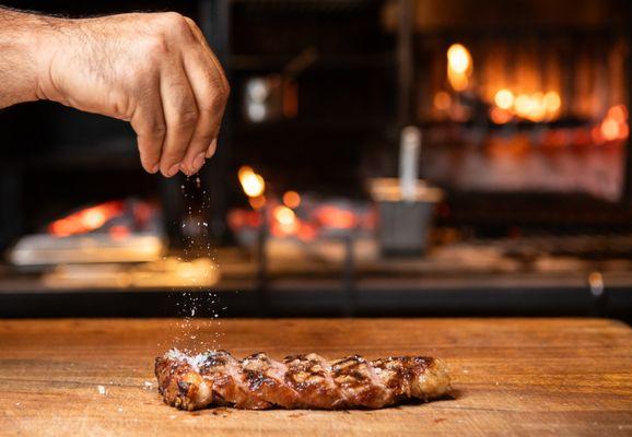 NY Strip resting while final touch of salt is added