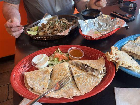 Steak quesadilla, next to chicken quesadilla, carnitas tacos in the back.