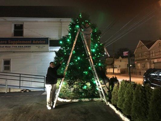 Our team is putting up holiday lights on the 20ft tree in our office parking lot.  Go team NYCBG!