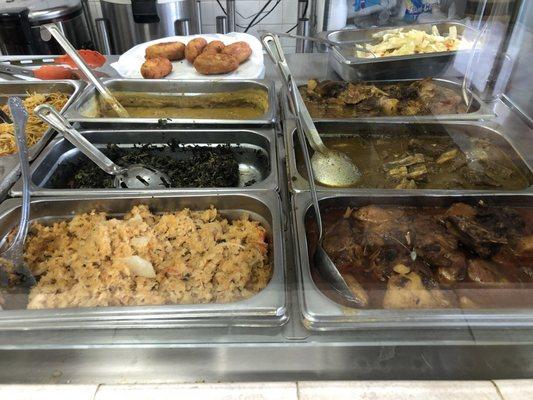 Clockwise from top left: fish cake, steam cabbage, curry chicken, curry goat, stew chicken, salt fish, callaloo, dhal