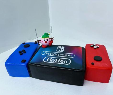 cake in the shape of a nintendo switch with fondant coverage and gum paste figures with edible image