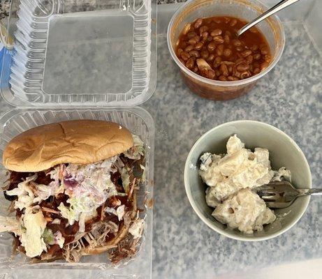 Pulled pork sandwich with potato salad and baked beans.