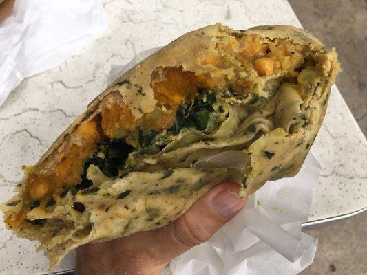 A half-eaten view of the vegetarian roti, which comes in a spinach wrap