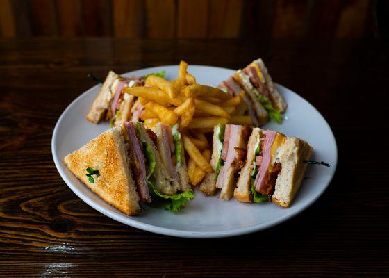 Our club sandwich - ham, turkey, American cheese, Swiss cheese, lettuce and tomato layered between three slices of toasted bread.