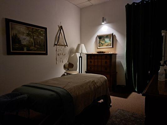 Massage therapy table, paintings of nature, dim lighting, cozy blanket