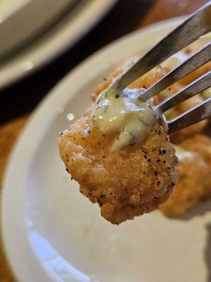 Close-up of a fork holding a Fried Catfish Bite.