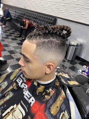 Skin fade, taper haircut with braids.