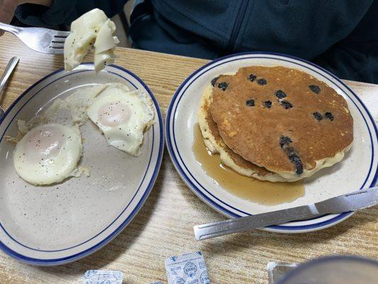 Half stack of blueberry pancakes and eggs basted