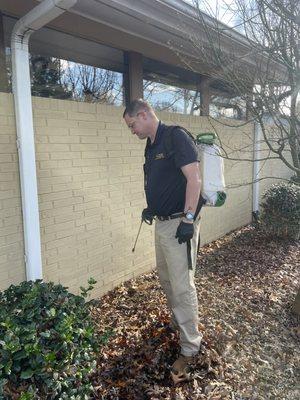 A technician applying liquid product to the base of the home.