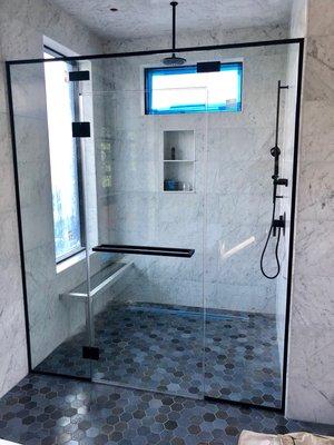 Matte black hardware shower door with 1/2" clear glass panels and 3/8" clear door, glass to glass hinges.