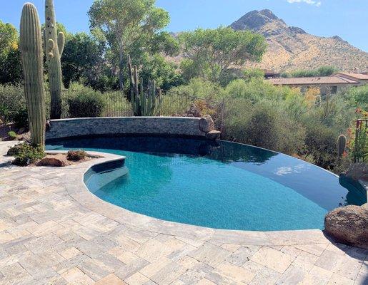 Remodeled negative edge pool in Troon. New travertine, pebble, depth conversion, waterfeature wall