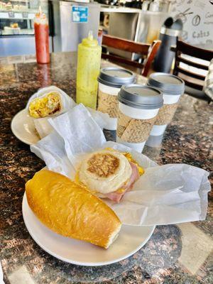 Fresh out the oven bolillo bread, a breakfast ham and egg sandwich, the breakfast burrito, that delicious green sauce, and some drinks.