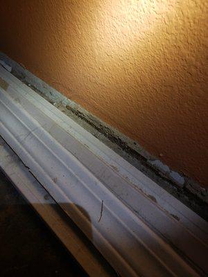 Damaged section of wall with baseboard laying in front of it.