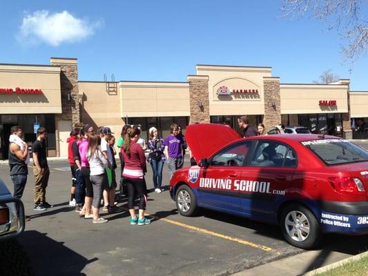 Teens getting a hands on lesson in car maintenance.