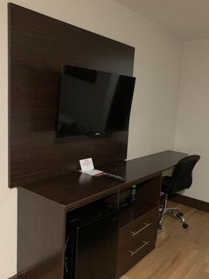 TV, internet monitor, desktop, with microwave oven and refrigerator underneath.