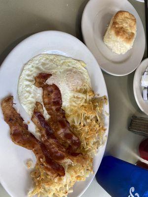 Eggs over easy, bacon, hash browns and a homemade biscuit