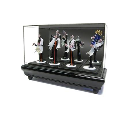 These figurines are displayed within a UV-coated plexi-glass enclosure, framed atop a sophisticated pedestal.