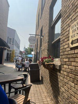 Several tables are located in the alley and might be shared with several eateries.