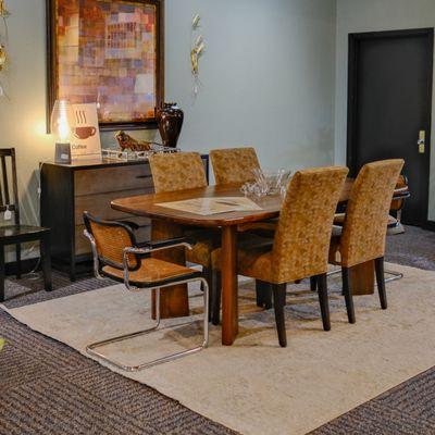 A dining room table set with chairs and an armchair, showcasing the elegance of midcentury modern design in furniture, with warm tones on th