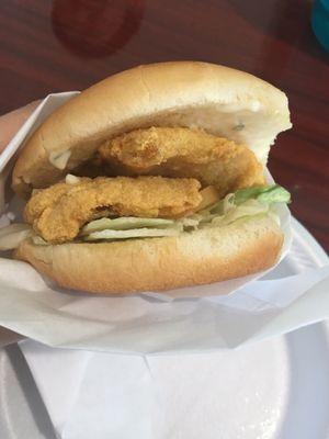 Inside the fish sandwich. Comes with iceberg lettuce, a tomato slice, tartar sauce spread, and two fish patties