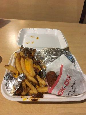 Tray with a spicy chicken sandwich, chili cheese fries, and hush puppies.