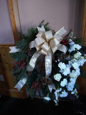 Fresh outside evergreen wreath with fresh flowers added to it for a sympathy piece.