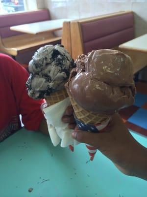 Cookies and cream on a waffle cone and chocolate ice cream on a waffle cone.