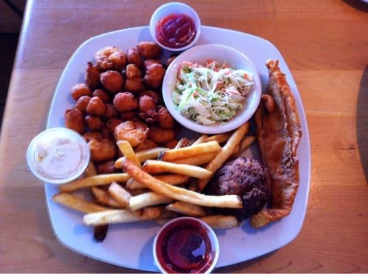 Platter with fried flounder, fried crab cake, fried shrimp, and fried bay scallops with French fries.