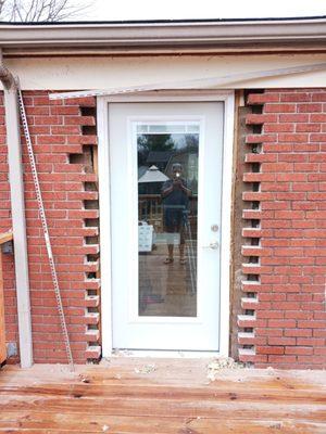 New back door installed on dinning room wall. Not finished around door molding or brick lain. Soffit not replaced.