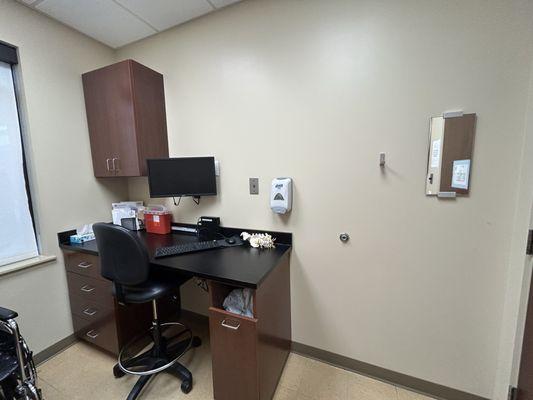 A patient treatment room, looking at the desk with a spine model sitting on top at Spine and Scoliosis Specialists - Greensboro office.