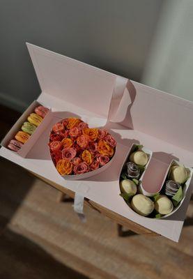 Box filled with French macaroons, white and milk Belgian chocolate covered strawberries arranged with fresh roses.