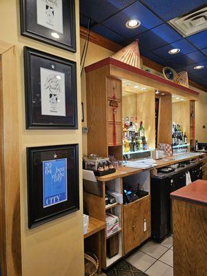 The bar of the restaurant with more framed awards hung on the column next to it.